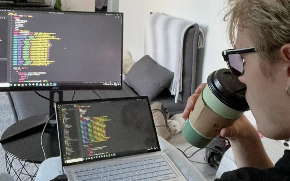 Pietari Risku working on Tsemp at a monitor and laptop, coffee cup in hand