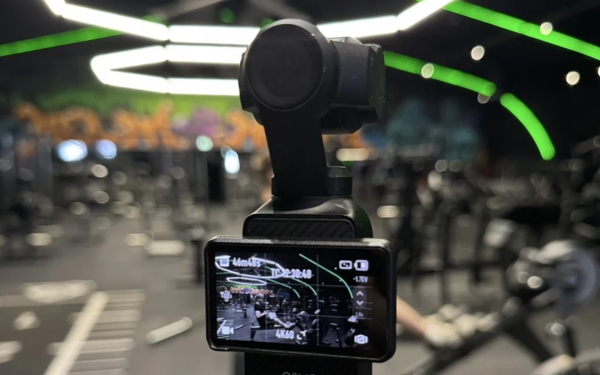 A handheld camera filming a Tsemp exercise video at the gym